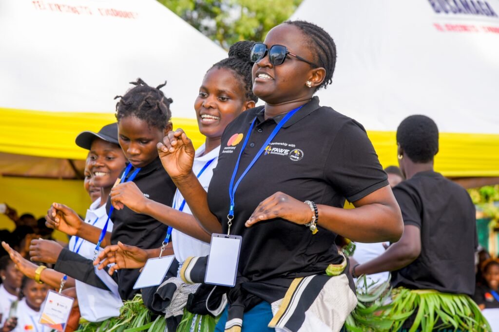 FAWE Uganda bursary recipients dancing and cheering at the Extended Orientation Programme opening