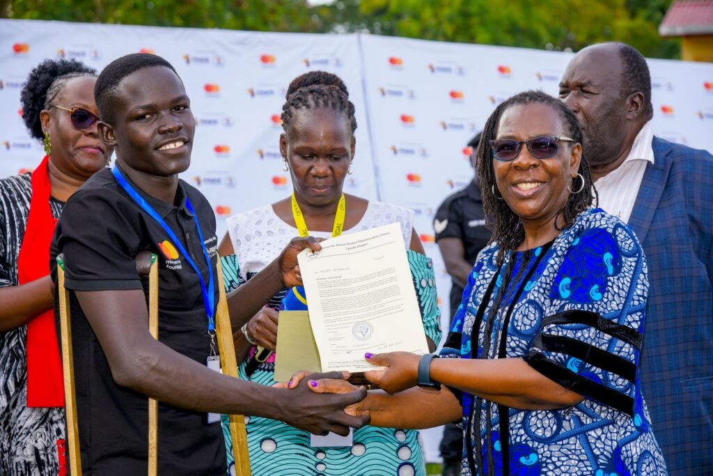 Olobo Shadrack, FAWE Uganda program participant, receives a FAWE Uganda bursary award letter from Dr Martha Muhwezi, FAWE Africa Executive Director at UTC Elgon, Mbale, Uganda